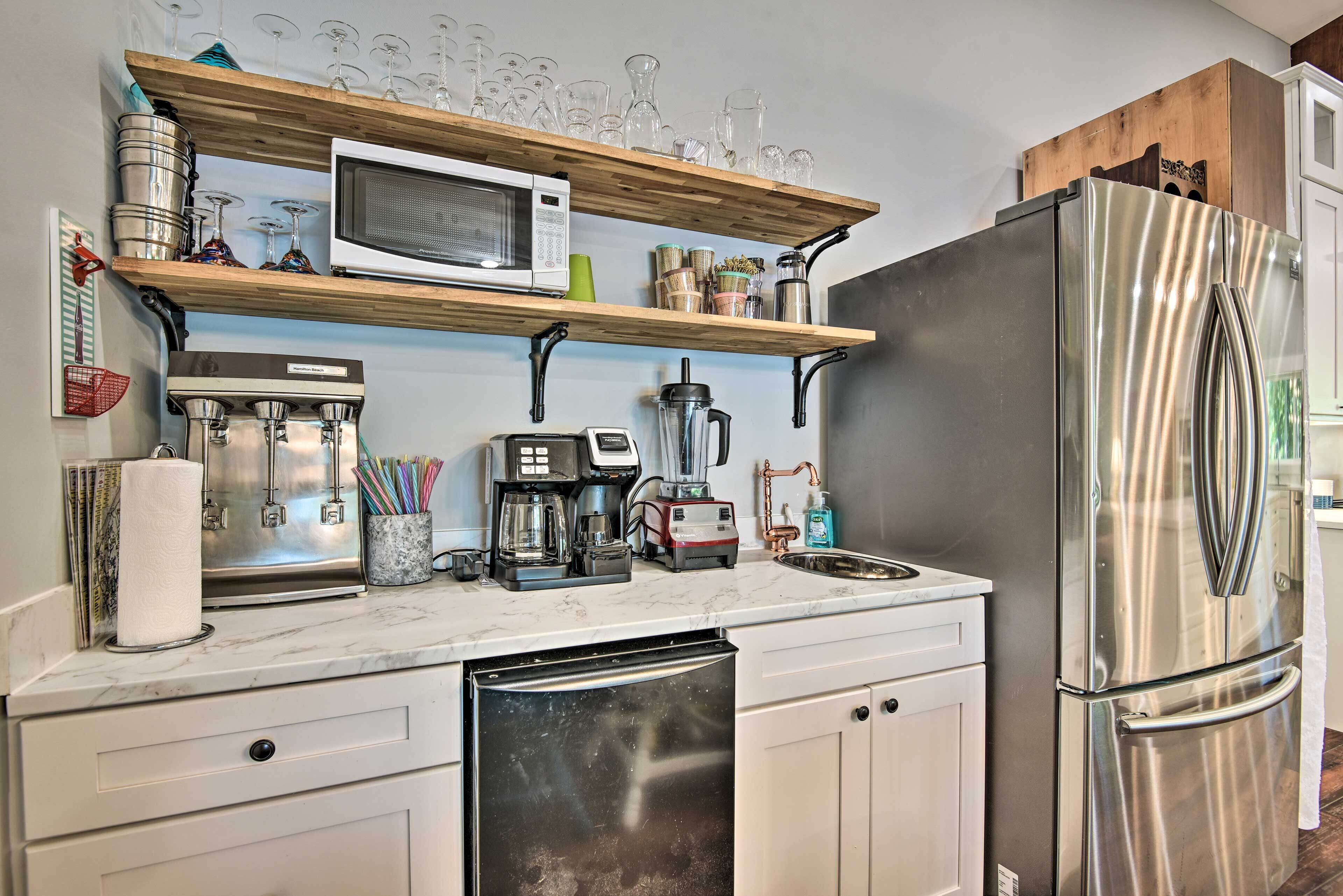 A modern kitchen with a stainless steel refrigerator, a microwave, a coffee maker, and a dishwasher.