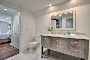 Une salle de bain avec des toilettes blanches, un meuble-lavabo en bois foncé et un grand miroir.