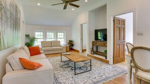 A living room with a sofa, coffee table, and a television in a modern apartment. - Quaint Goshen Apartment w/ Patio! (Goshen)