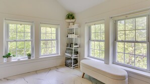 A room with large windows, a white bench, and a shelving unit with folded items. - Quaint Goshen Apartment w/ Patio! (Goshen)