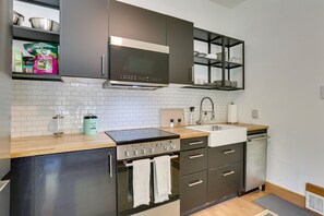 Een moderne keuken met donkere kastjes, een roestvrijstalen oven, een magnetron en een spoelbak.
