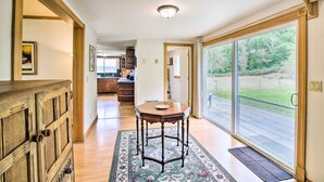A spacious hallway with a wooden cabinet, a dining table with a rug, and a large sliding glass door leading to a backyard.