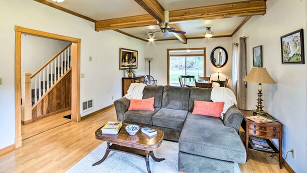 A living room with a wooden ceiling, a gray sectional sofa, a wooden coffee table, and a staircase.