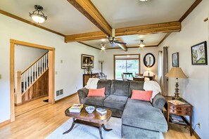 Ein Wohnzimmer mit Holzboden, einem grauen Ecksofa, einem Holztisch und einer Treppe.