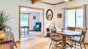 A dining area with a wooden table and chairs, a blue armchair, and a mirror on the wall.