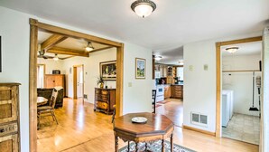 A spacious living room with hardwood floors, a wooden dining table, and a large rug.