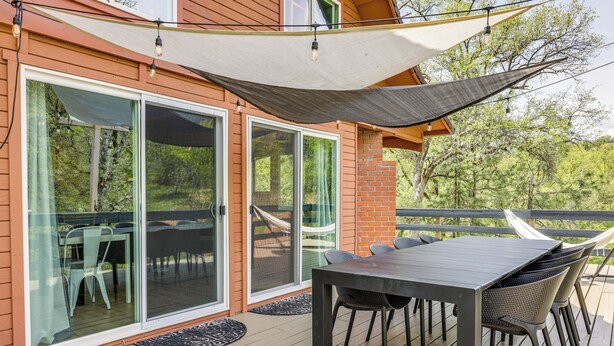 A deck with a table and chairs, a hammock, and a large window overlooking greenery. - Groveland Vacation Rental ~ 24 Mi to Yosemite! (Groveland)