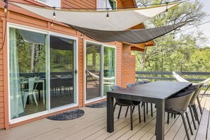 A deck with a table and chairs, a hammock, and a large window overlooking greenery. - Groveland Vacation Rental ~ 24 Mi to Yosemite! (Groveland)