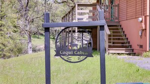 A Coqui Cabin sign with a cabin in the background. - Groveland Vacation Rental ~ 24 Mi to Yosemite! (Groveland)
