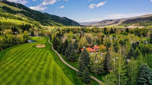 A golf course with a red-roofed building surrounded by trees and a mountainous backdrop. - Townhome ~ 4 Mi to Beaver Creek & 8 Mi to Vail! (Avon)