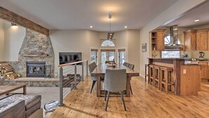 A spacious living area with a stone fireplace, wooden dining table, and bar stools. - Townhome ~ 4 Mi to Beaver Creek & 8 Mi to Vail! (Avon)