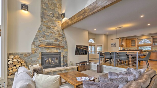 A spacious living area with a stone fireplace, a wooden ceiling beam, a sofa, and a coffee table. - Townhome ~ 4 Mi to Beaver Creek & 8 Mi to Vail! (Avon)