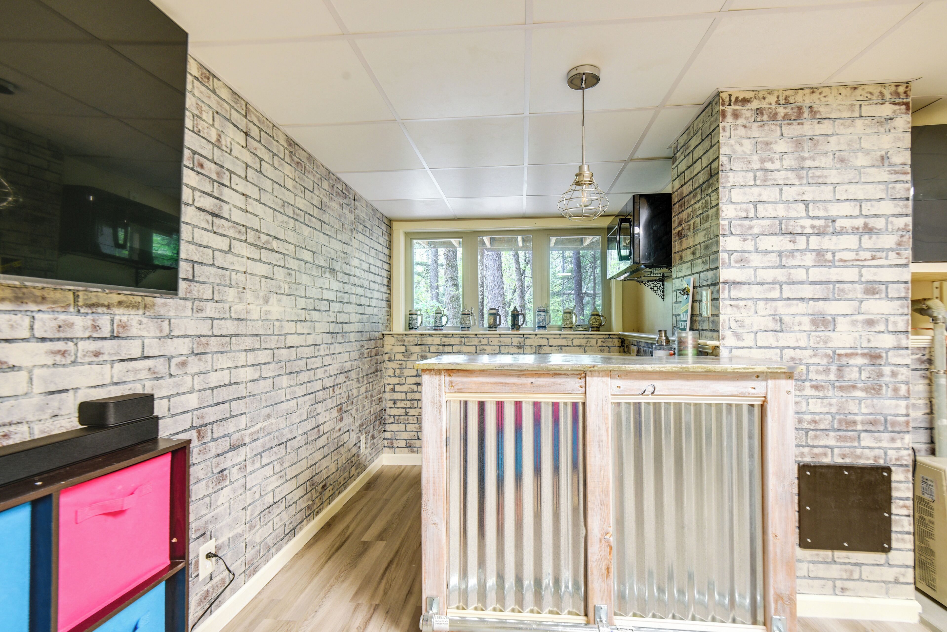 A kitchen with exposed brick walls, a wooden countertop, and a large window.