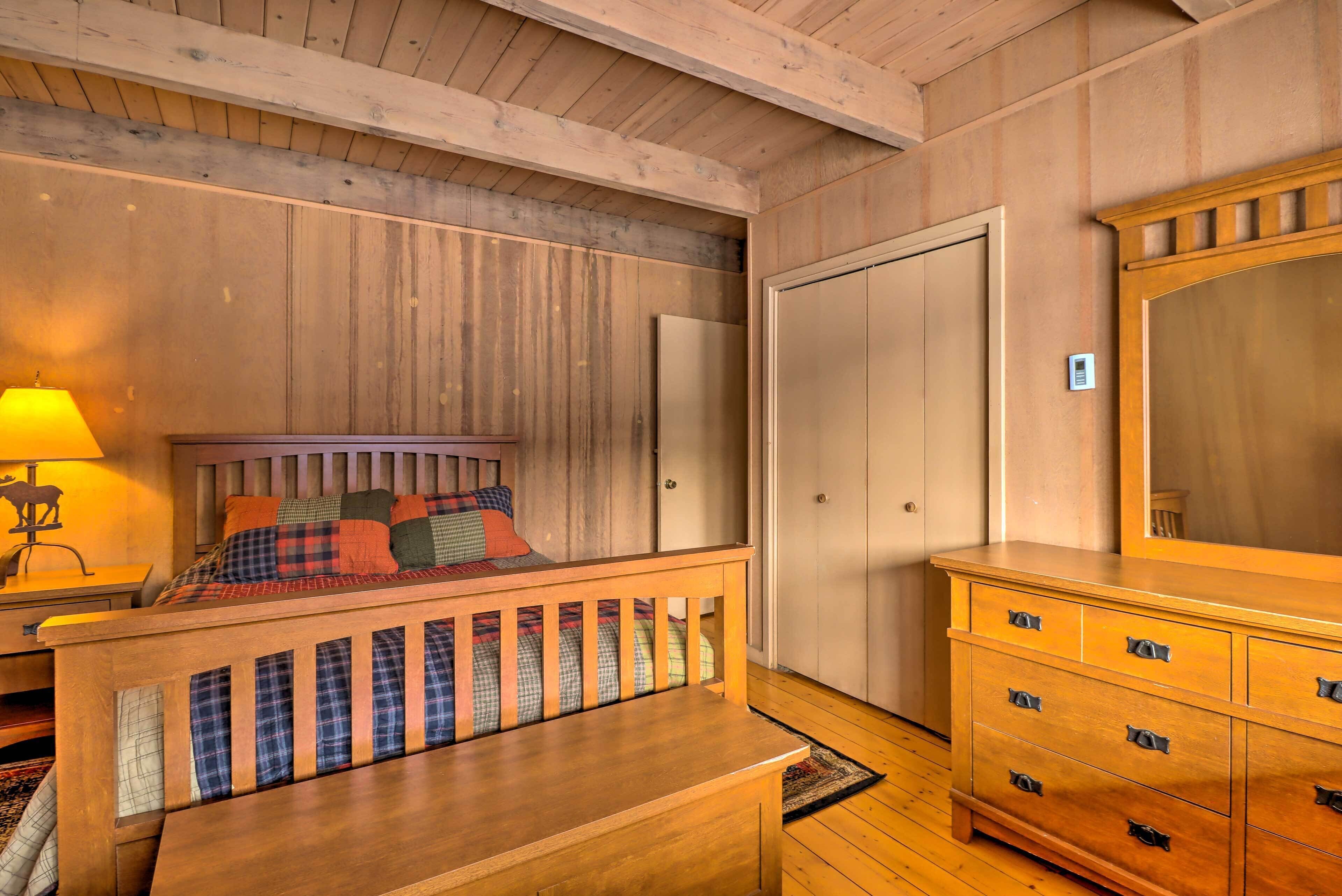 Ein Zimmer mit Holzwänden, einem Bett, einer Kommode und einem Spiegel.