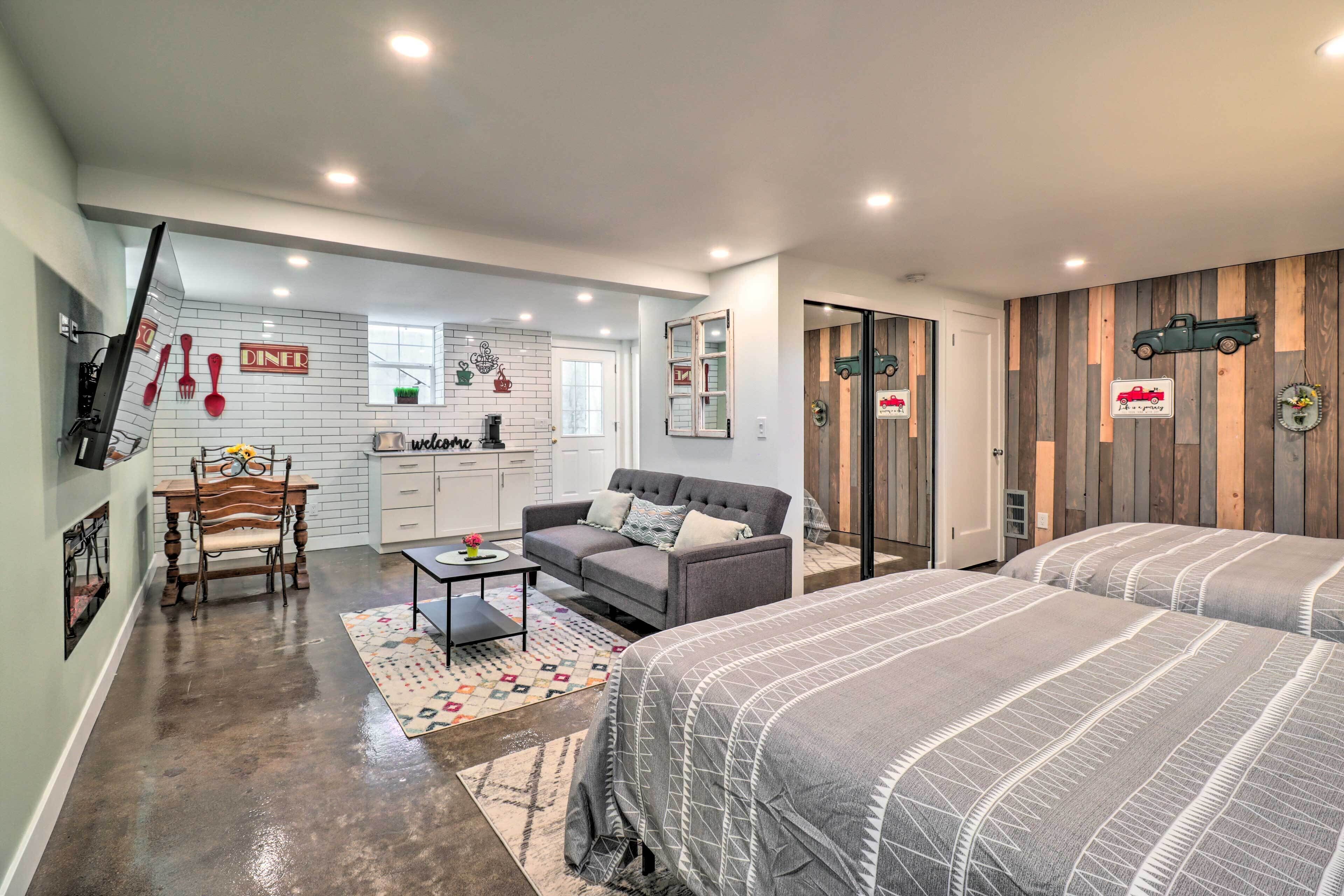 A modern interior with a dining area, sofa, and two beds.