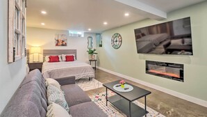A modern bedroom with a bed, a sofa, a TV, and a fireplace. - Ski & Hike: Cozy Dtwn Reno Studio w/ Fireplace (Reno)
