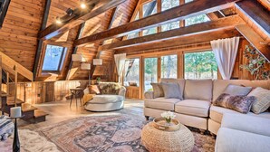 Un vaste espace de vie de style loft, doté d’un plafond haut, de poutres apparentes, de grandes fenêtres, d’un canapé confortable et d’une cheminée.