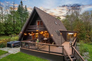A wooden cabin with a deck, hot tub, and string lights. - Rustic Lafayette A-frame Cabin w/ Game Room! (LaFayette)