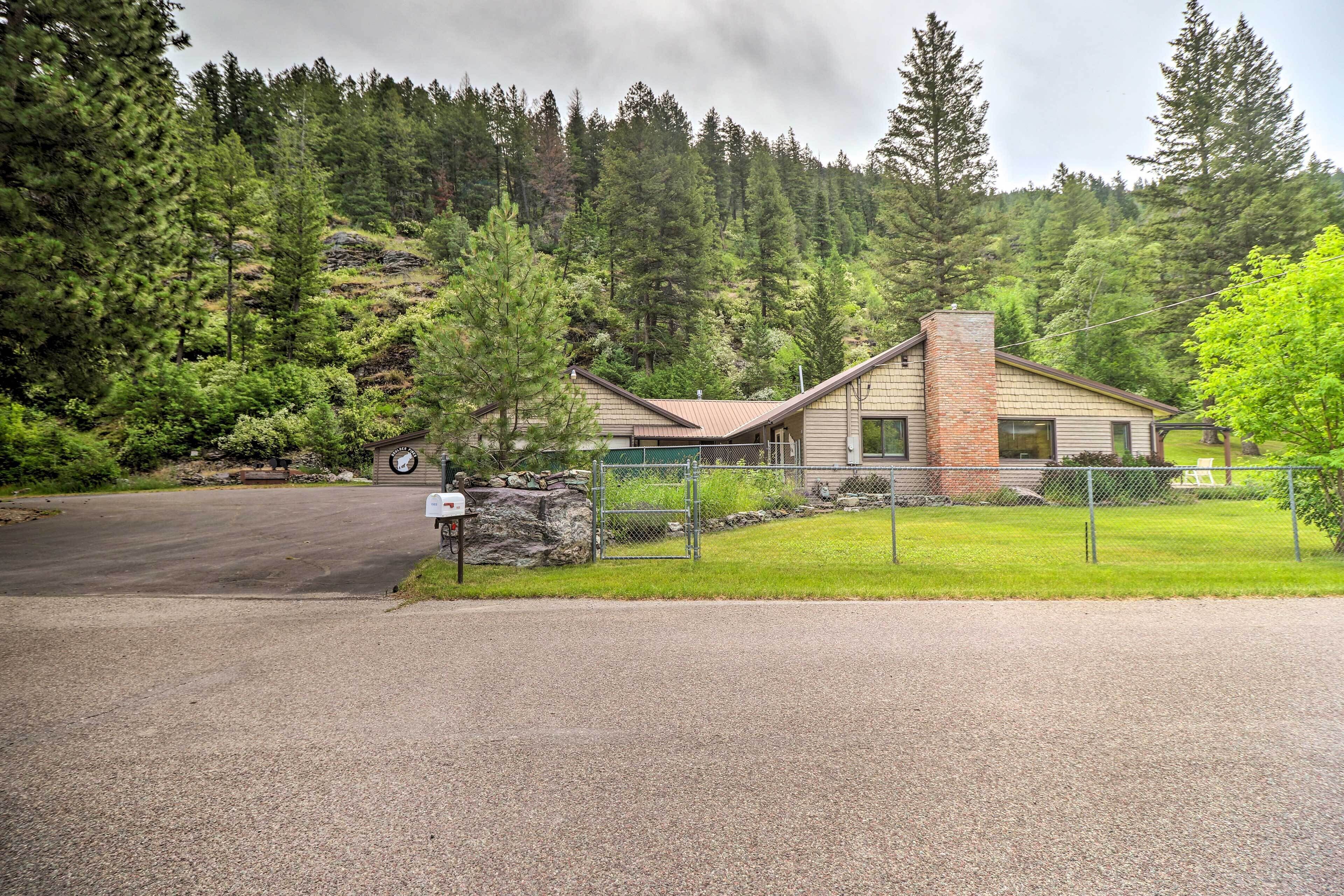 A lodge with a brick chimney, surrounded by a forested hillside.