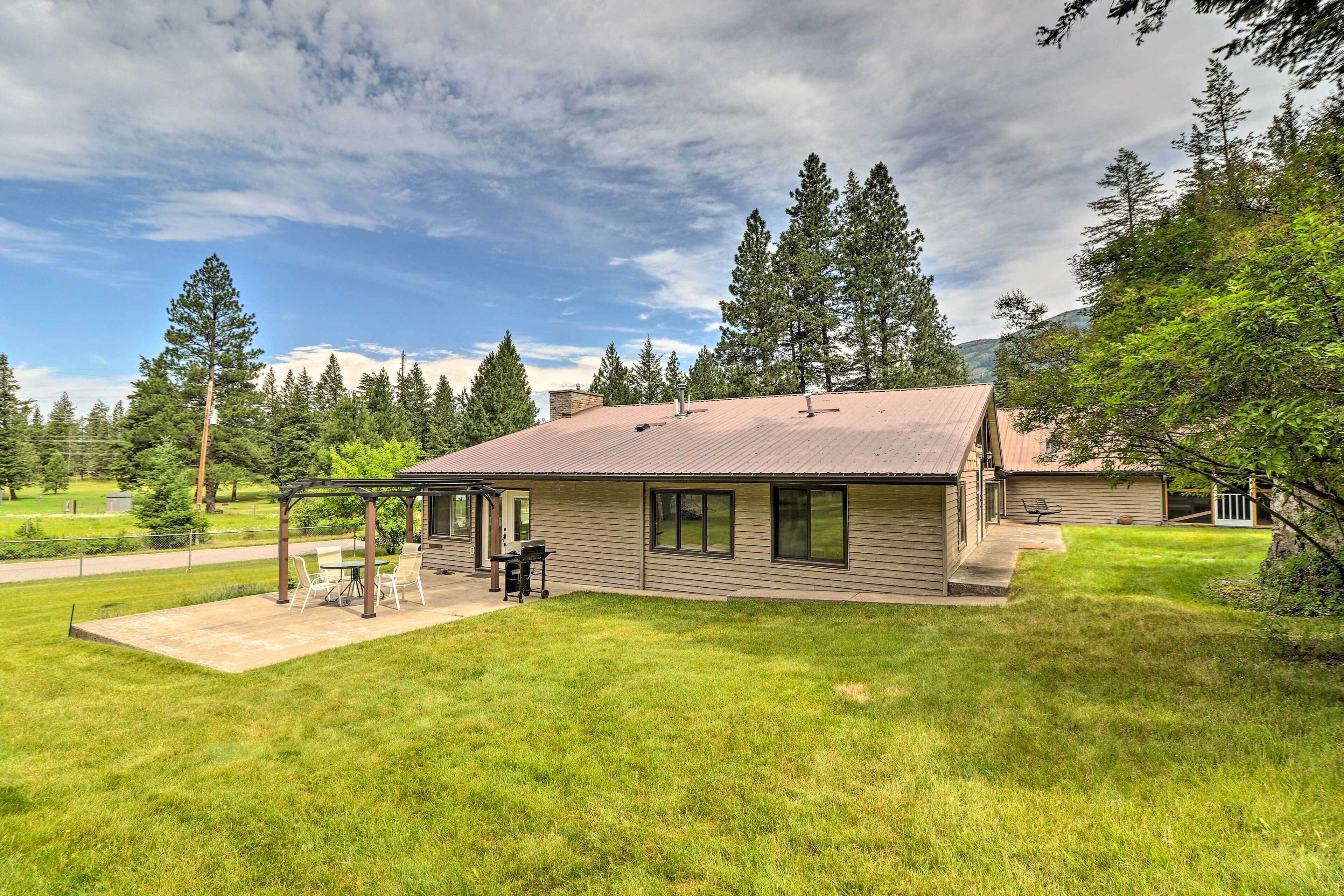 A single-story house with a covered patio, a lawn, and a mountain backdrop.