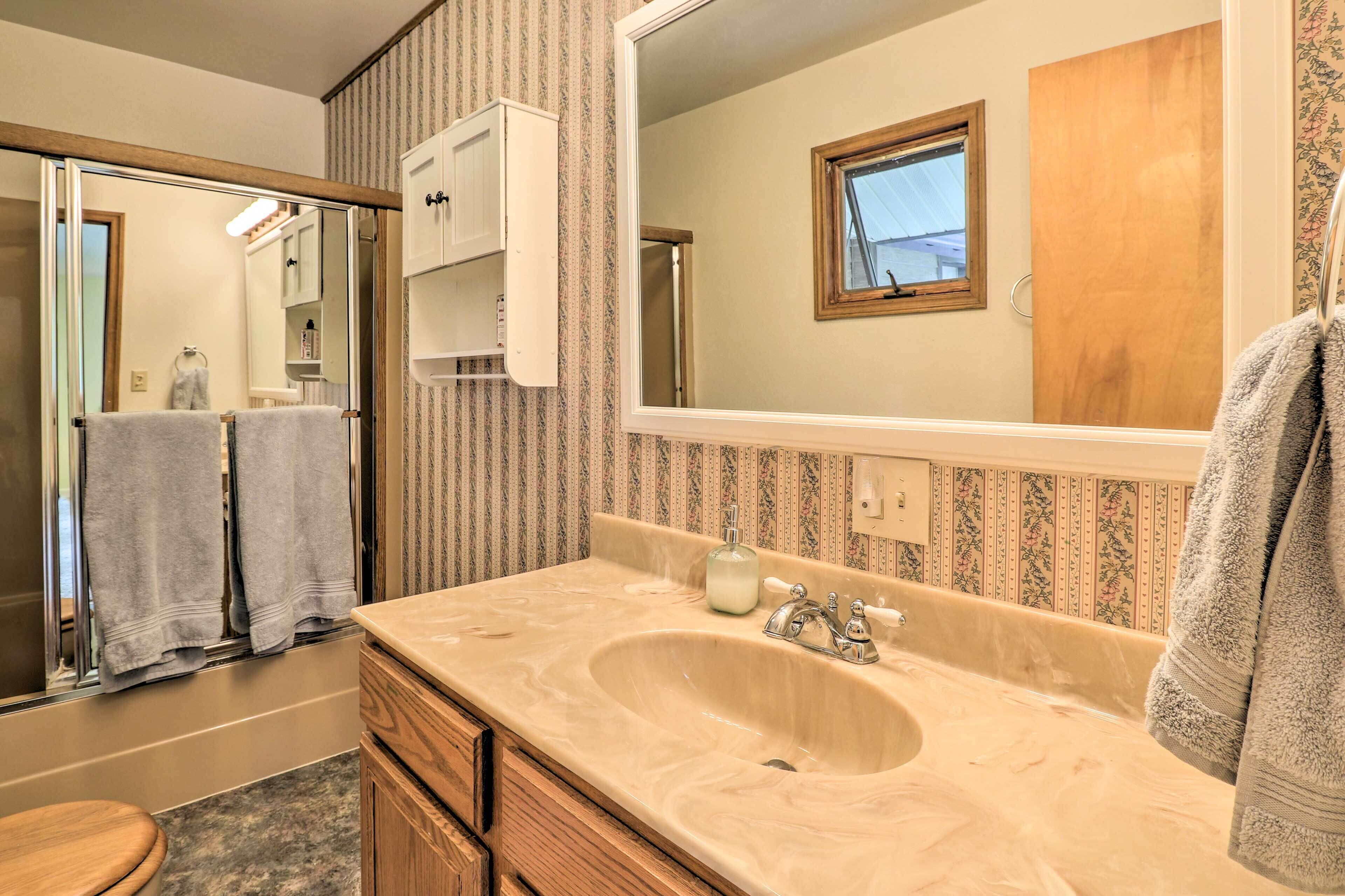 A bathroom with a large mirror, a sink, wooden cabinets, and a toilet.