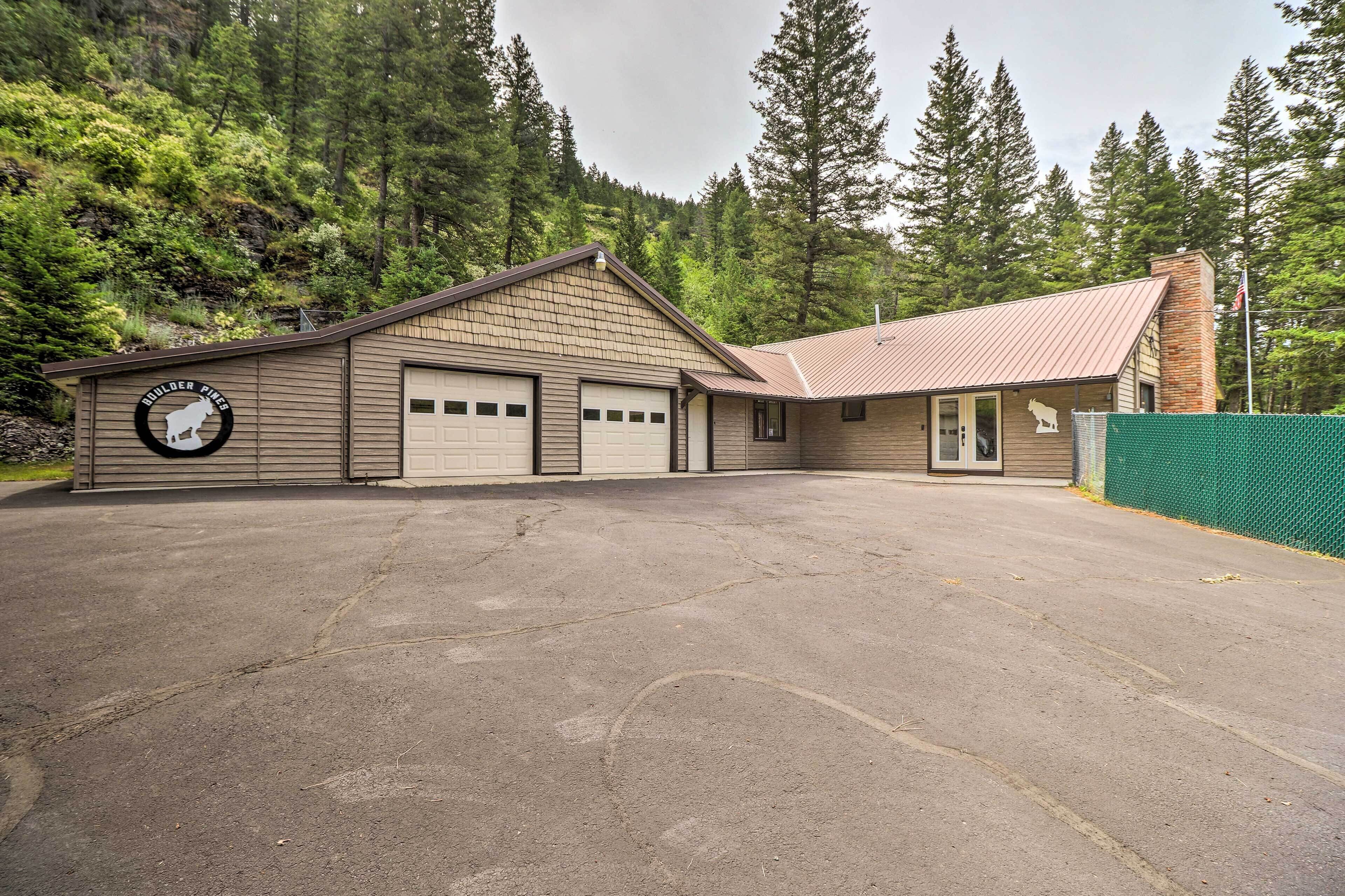 A building with a garage and a small attached structure, surrounded by a forested area.