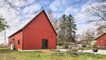 Rustic barn-style building with a gable roof, featuring a front door and steps leading up to it.