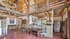 Eine geräumige Küche mit Holztisch und -stühlen, einem Edelstahlkühlschrank und einer Erkergalerie mit Geländer.