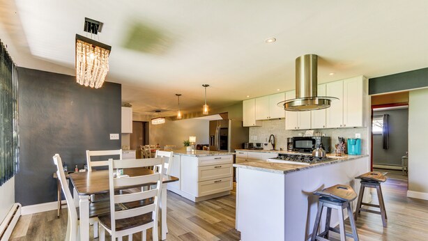 A modern kitchen with a central island, white cabinetry, and a chandelier. - Indian Lake Vacation Rental w/ Fire Pit & Sauna (Lakeview)