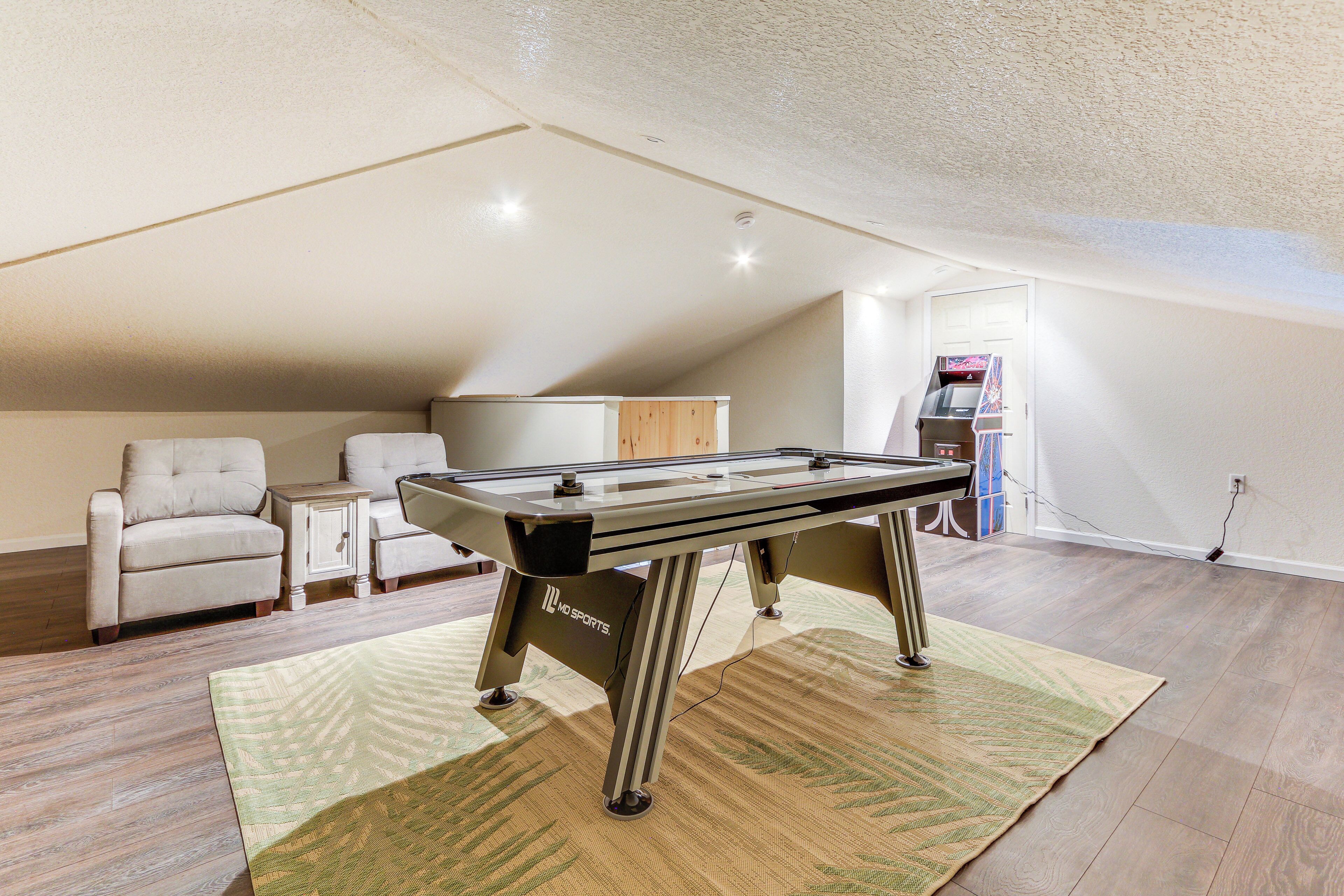 A pool table in a room with a sloped ceiling, a sofa, and a cabinet.