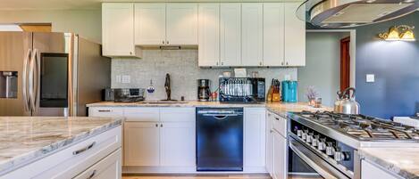 A modern kitchen with white cabinets, a dishwasher, a stove, and a refrigerator.