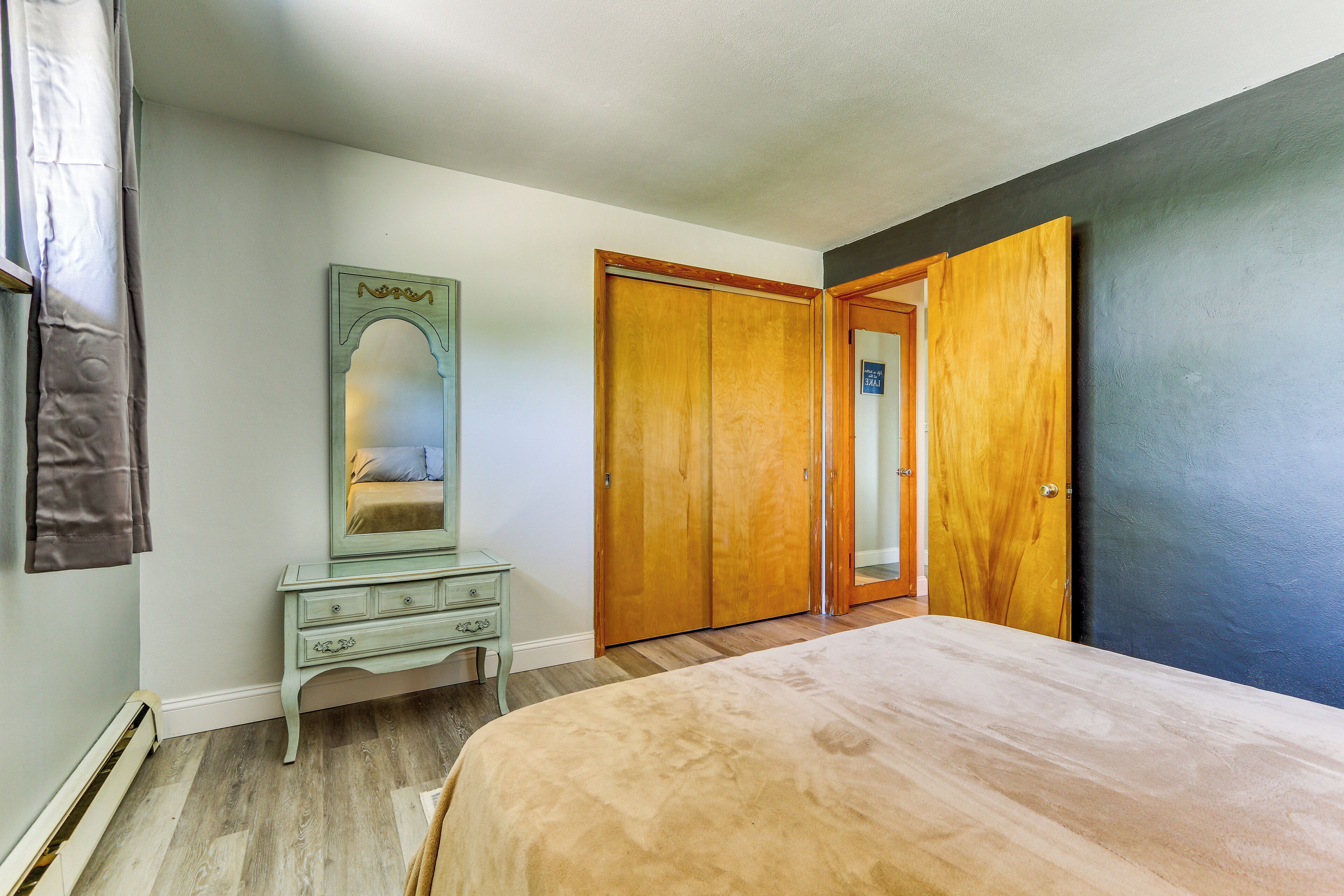 A bedroom with a bed, a dresser, a mirror, and a wardrobe.