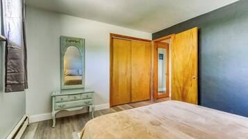 A bedroom with a bed, a dresser, a mirror, and a wardrobe.