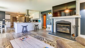 A modern kitchen with white cabinets, a central island, and pendant lighting. - Indian Lake Vacation Rental w/ Fire Pit & Sauna (Lakeview)