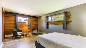 A bedroom with a bed, two chairs, a small table, a lamp, and a window with curtains. - Indian Lake Vacation Rental w/ Fire Pit & Sauna (Lakeview)
