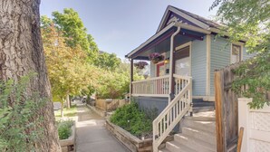 Ein zweistöckiges Haus mit Veranda, Holzzaun und Baum im Vordergrund.