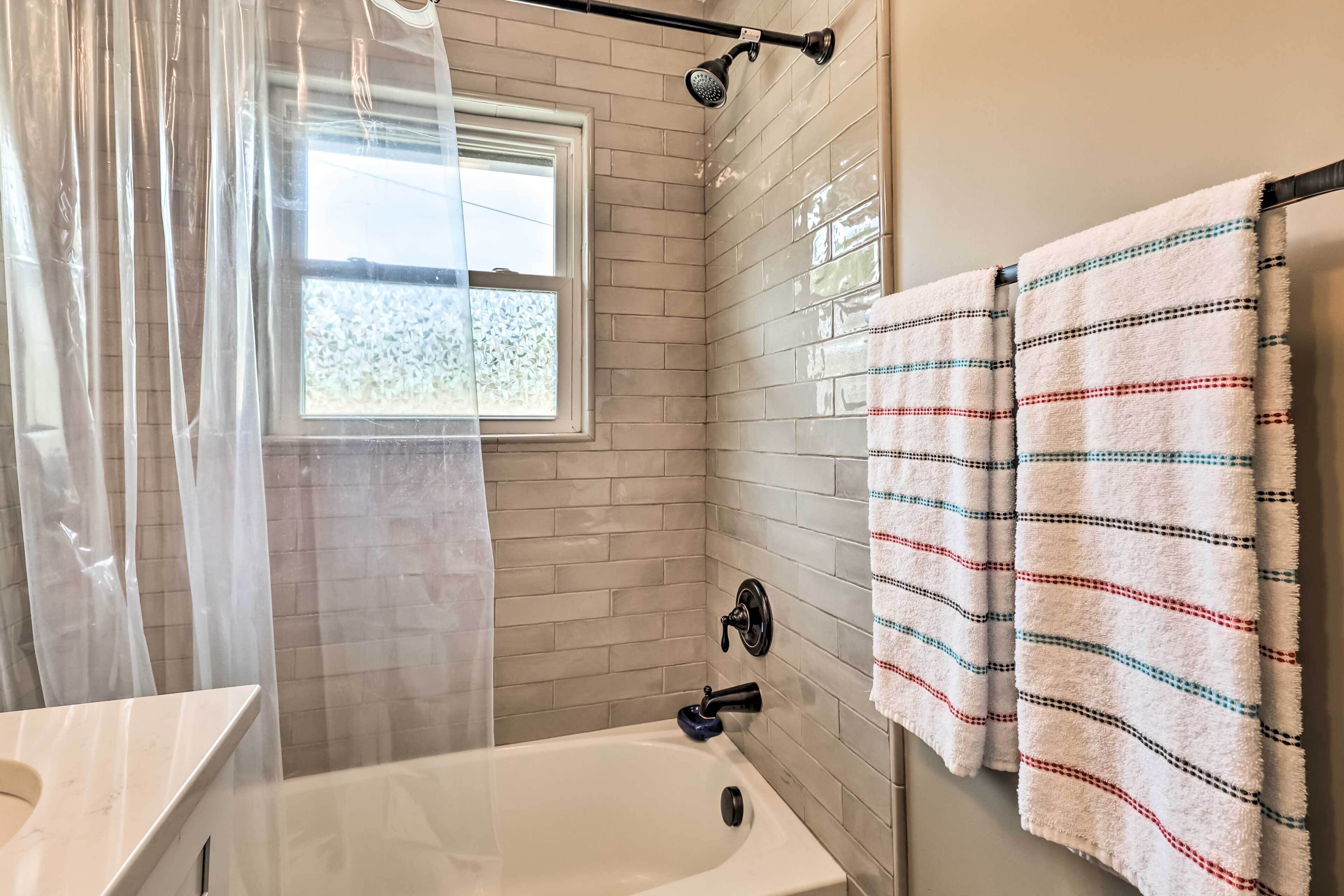 Ein Badezimmer mit einer Badewanne, einem Fenster mit Aussicht und einem Handtuchhalter mit gestreiften Handtüchern.