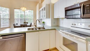 A modern kitchen with white cabinets, a stainless steel microwave, and a built-in oven. - Port St Lucie Home ~ 3 Mi to Botanical Gardens! (Port Saint Lucie)