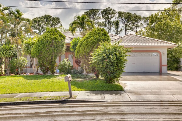A residential property with a garage, a well-maintained lawn, and various trees.