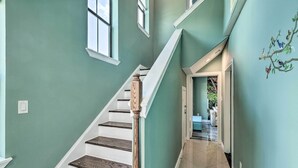 A staircase with white steps and wooden balusters, leading to a landing with a view of the outdoors. - Chic Midtown House ~ 2 Mi to Dtwn Houston! (Houston)
