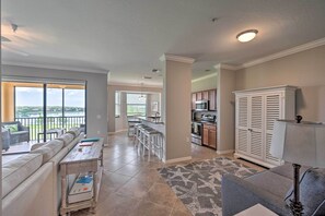 A spacious living area with a sofa, a small table, and a kitchen in the background. - Bonita Springs Condo w/ Lake & Golf Views! (Naples)
