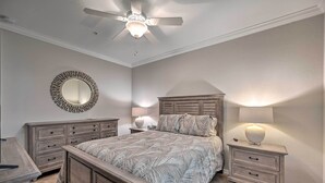 Un dormitorio con una cama, mesitas de noche, un espejo y un ventilador de techo.