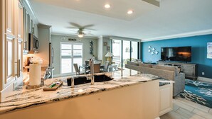A modern kitchen with a central island, built-in appliances, and a dining area with a ceiling fan.