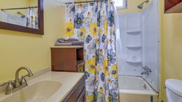 A bathroom with a sink, toilet, shower, and a mirror.