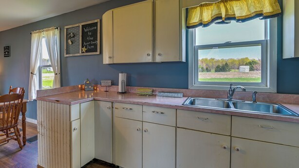 A kitchen with white cabinets, a sink, and a window with a view of the outdoors. - Upstate New York Vacation Rental Near Cooperstown! (Jordanville)