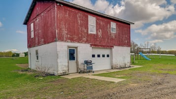 A red and white building with a garage, a small outdoor grill, and a playground in the background.