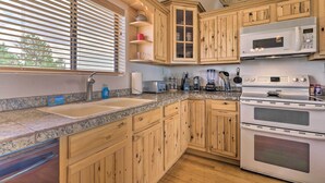 Een keuken met houten kastjes, een granieten aanrechtblad, een inbouwoven en een magnetron.
