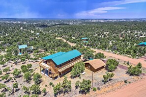 Un edificio de madera grande con techo azul, rodeado de árboles y un paisaje montañoso.