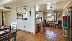 A spacious kitchen with a dining area, featuring a stone-tiled floor, wooden chairs, and a rustic aesthetic. - Eclectic Tucson Home 2 Mi to Saguaro National Park (Tucson)