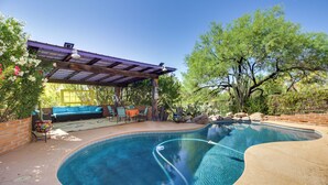 A swimming pool with a curved edge, a covered seating area with a table and chairs, and a pergola overhead. - Eclectic Tucson Home 2 Mi to Saguaro National Park (Tucson)